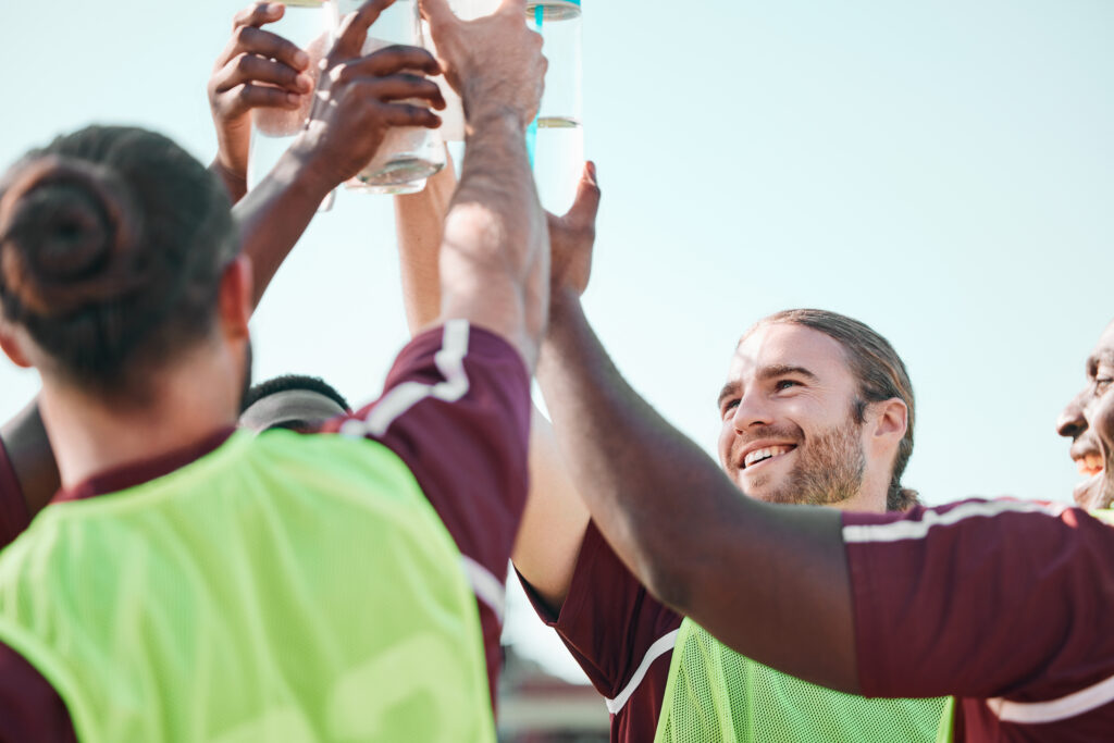 Une équipe d'hommes sportifs trinquent avec les gourdes d'eau.