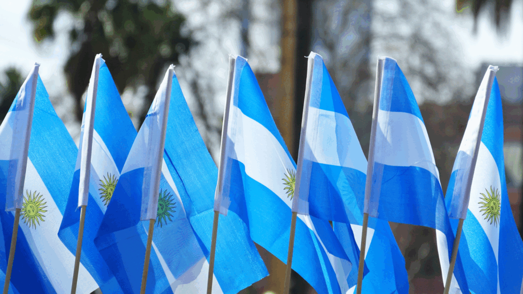 Une rangée de drapeau de l'Argentine. L'arrière-plan est flou, mais laisse apparaître des palmiers.