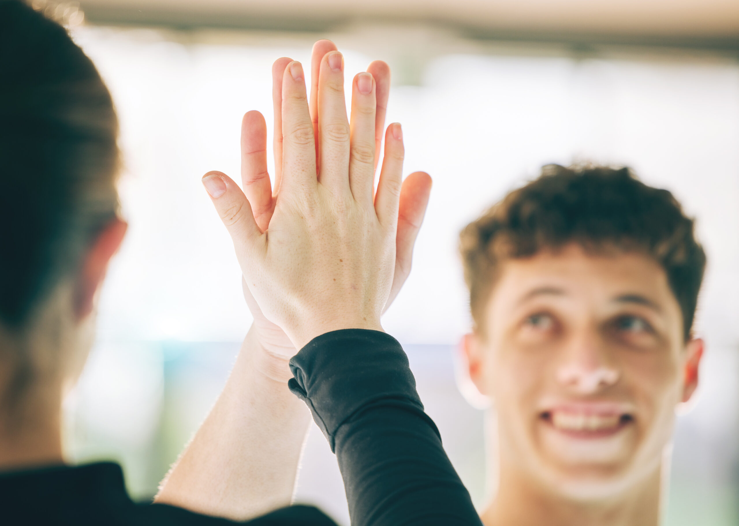 une personne de dos et un jeune homme de face font un high-five